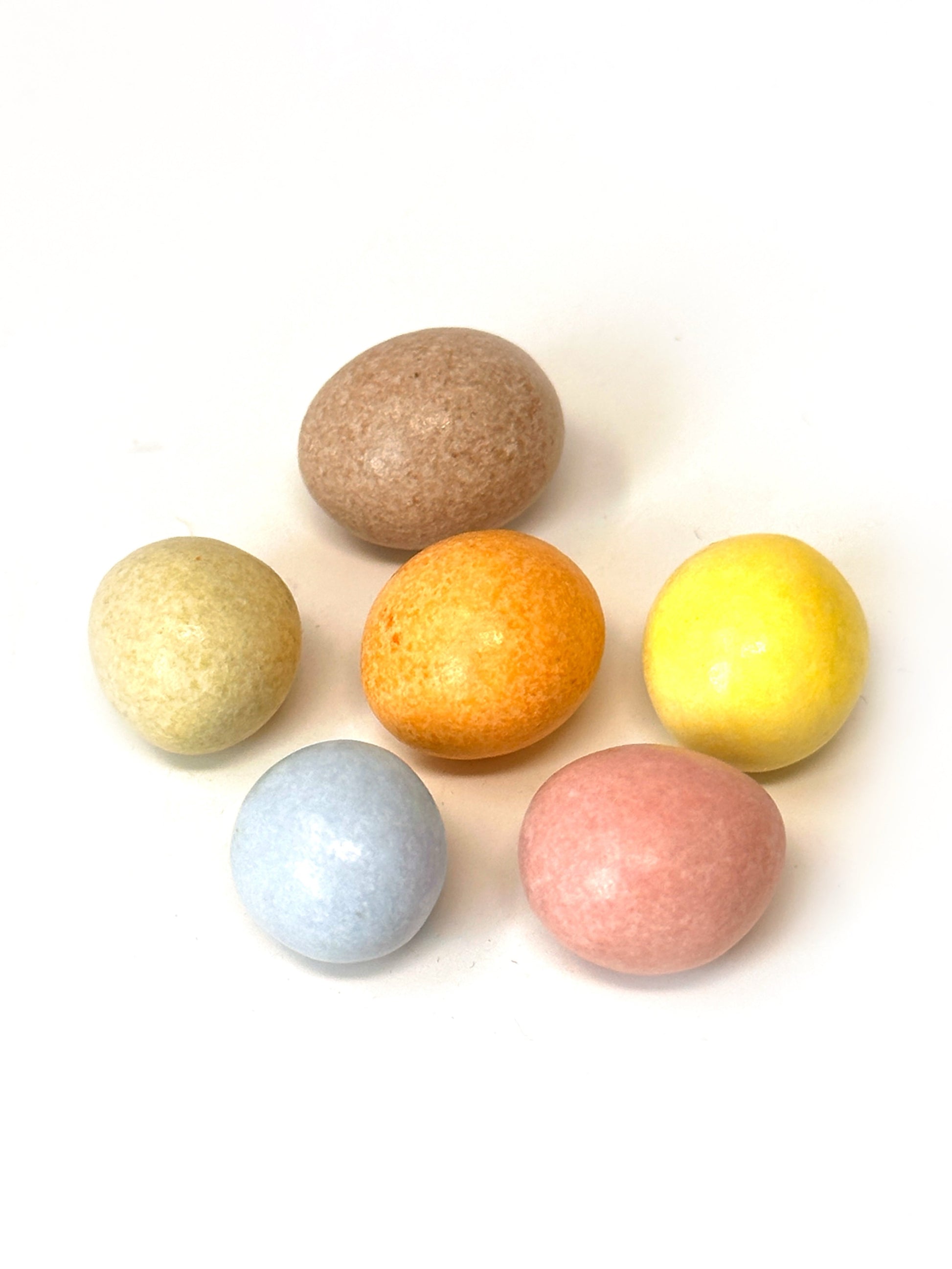 Gros plan sur les billes de Coq’n Choc aux couleurs végétales naturelles, enrobées de chocolat au lait et noir bio.