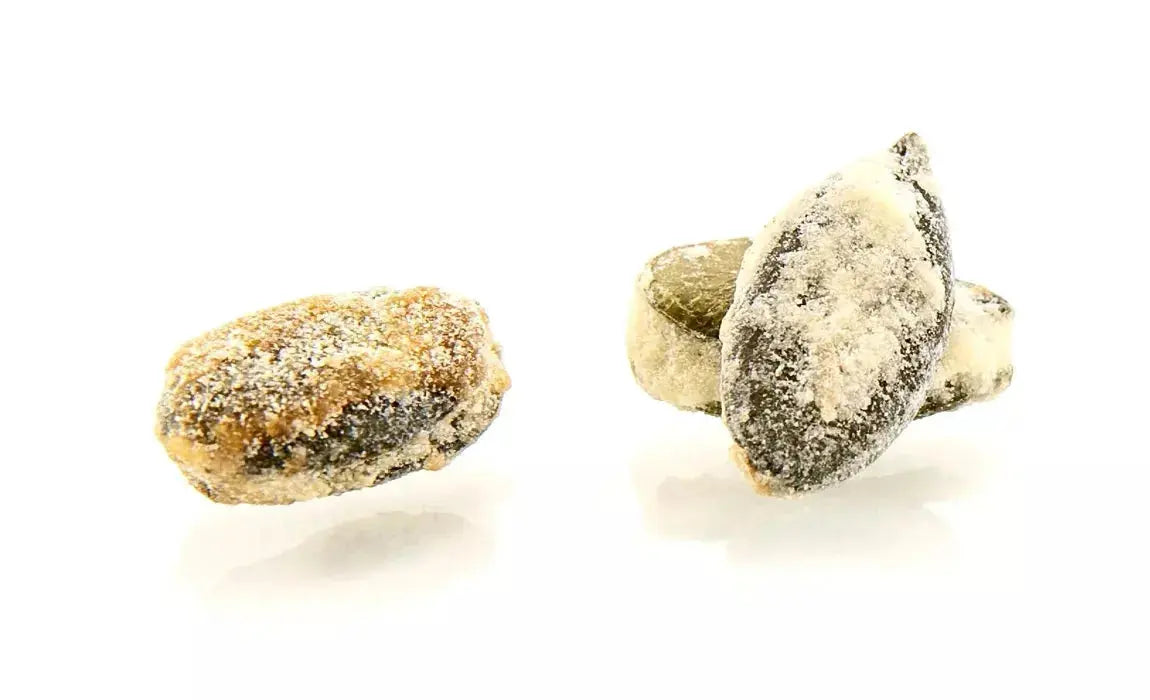 Graine de courge croquante enrobée d’une fine couche de caramel doré, offrant une texture croustillante et une saveur légèrement sucrée, sur fond blanc. bio