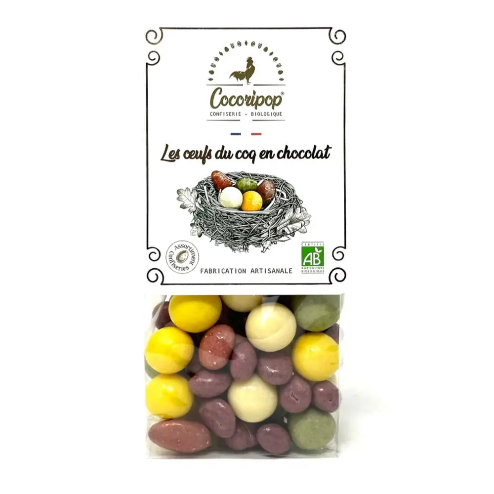 Assortiment Œufs du Coq en Chocolat, Mélange festif d’œufs en chocolat blanc, lait et noir, associant noisettes, amandes, raisins et céréales croustillantes, idéal pour une dégustation gourmande et authentique. bio