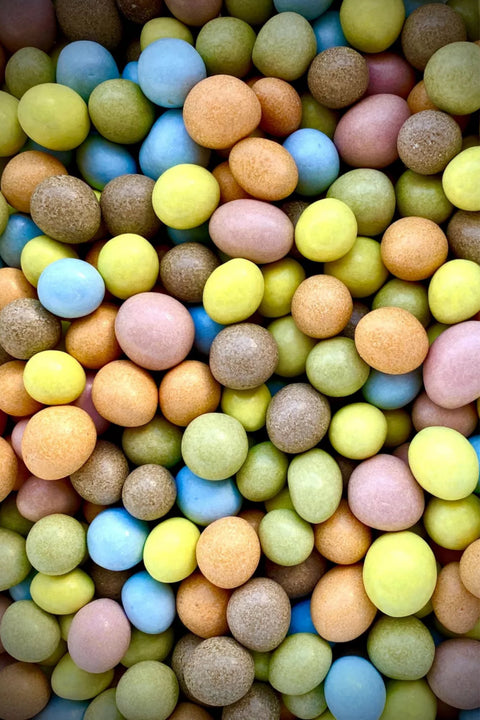 Coupe detaillee montrant la cacahuete torrefiee, l’enrobage de chocolat et la coque drageifiee naturelle, confiserie artisanale inspiree des MMs.