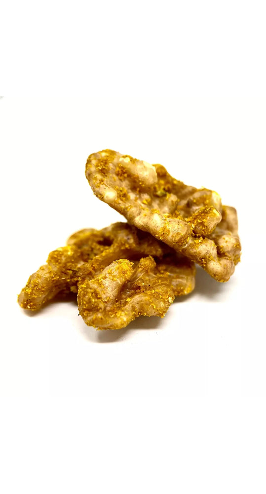 Cerneau de noix du Berry croquant, enrobé d’un mélange d’épices curry bio, révélant des notes chaudes et parfumées, sur fond blanc. bio