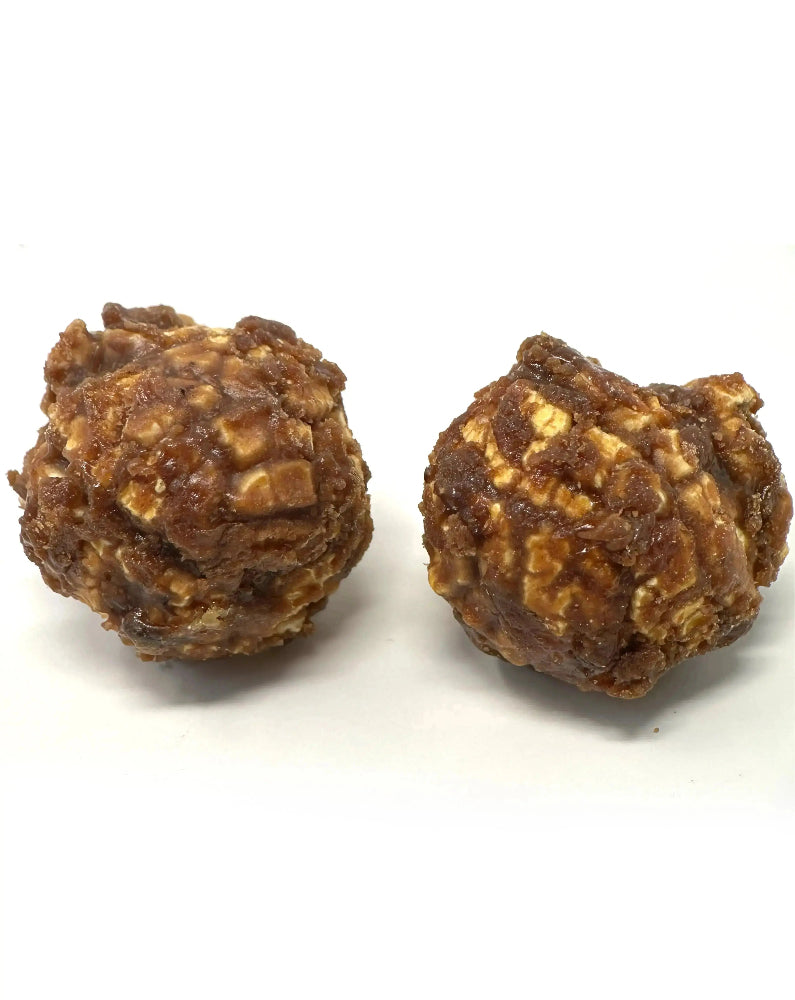 Grain de popcorn croustillant enrobé de caramel fondant et d’un nappage de chocolat, pour une gourmandise sucrée irrésistible, sur fond blanc.