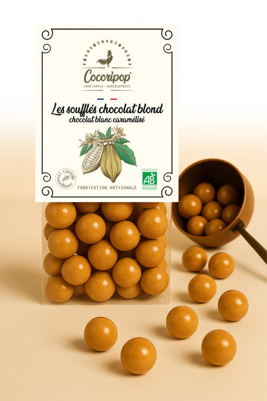 Nouveauté : Les Soufflés Chocolat Blond – billes soufflées croustillantes enrobées de chocolat blanc caramélisé, gourmandise fondante et croquante, présentée sur fond blanc. BIO