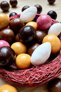 Confiserie artisanale française composée d'amandes dragéifiées et de billes de céréales croustillantes enrobées de chocolats bio, fabriquée à Saint-Germain-du-Puy.