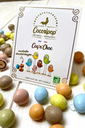 Spécialité artisanale française élaborée à Saint-Germain-du-Puy, associant cacahuètes bio, chocolat fondant et dragéification traditionnelle aux couleurs naturelles.