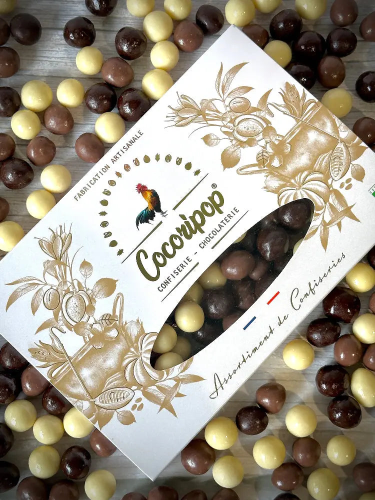 
Coffret Noisette Trio Chocolat – assortiment de chocolats au lait, noir et blanc, sur fond blanc.Coffret gourmand de noisettes enrobées de chocolat noir, au lait et blanc, présenté sur fond blanc.Coffret Noisette Trois Chocolats – chocolats artisanaux au lait, noir et blanc, par Cocoripop.Coffret artisanal de noisettes croquantes enrobées de chocolat noir, lait et blanc. BIO