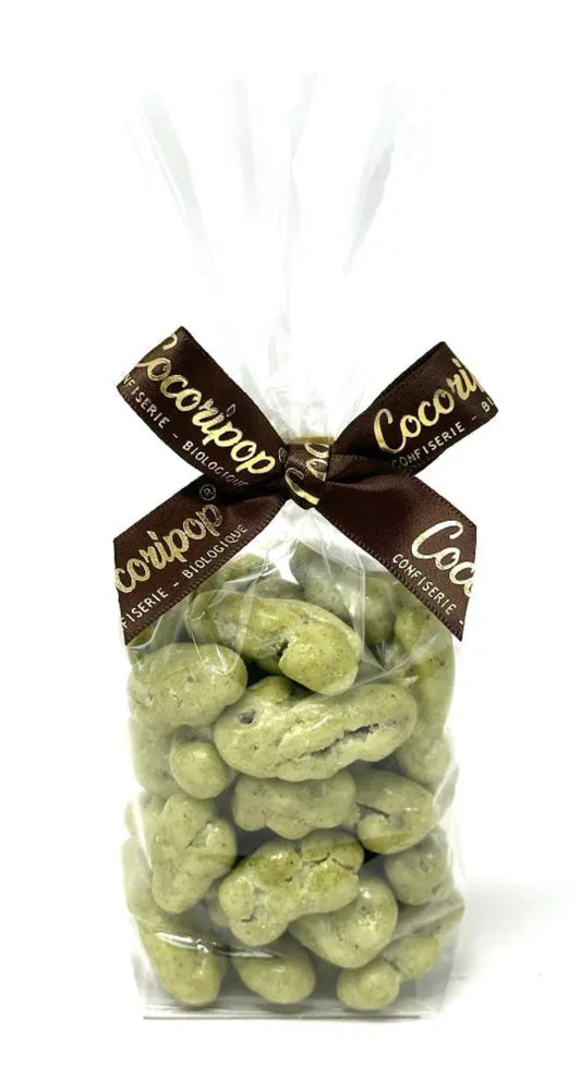 Noix de pécan bio enrobées de chocolat blanc et pâte de pistache artisanale, délicatement poudrées, présentées sur fond clair