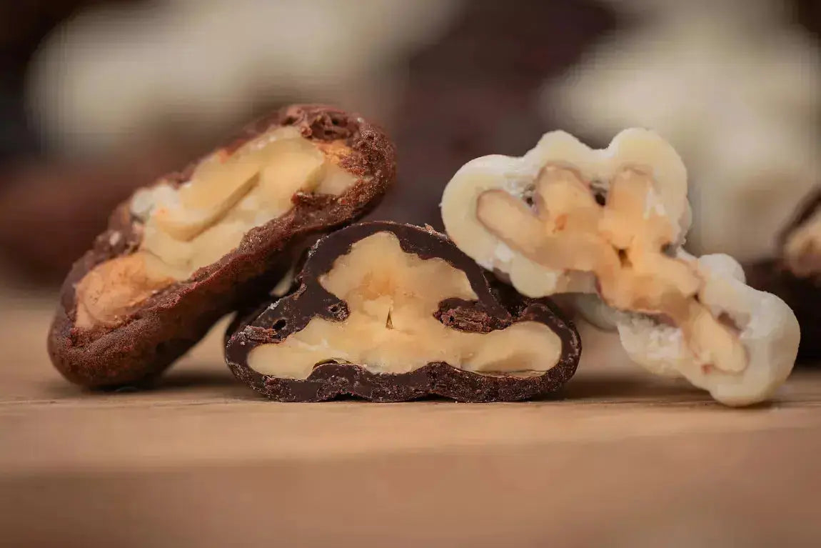 Cerneau de noix du Berry croquant, délicatement enrobé de chocolat blanc onctueux et saupoudré d’une fine couche de sucre glace, offrant une expérience fondante et raffinée, sur fond blanc. bio