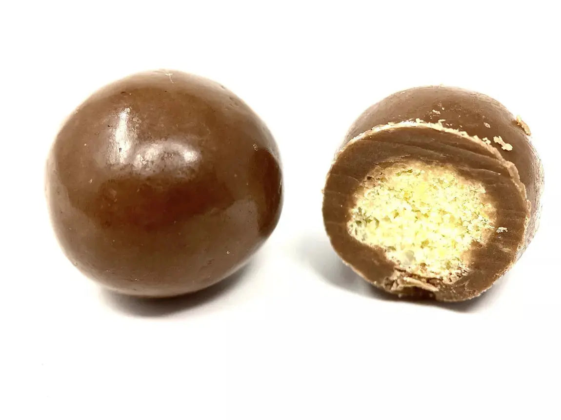 Bille de maïs soufflée croustillante, enrobée d’un chocolat au lait onctueux, révélant une texture fondante et un goût doux et équilibré, sur fond blanc. bio